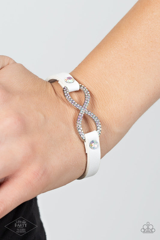 Innocent Until Proven GLITZY! - Multi Paparazzi Bracelets a skinny strip of white leather attaches to a silver infinity symbol encrusted in glittery iridescent rhinestones. Flanked by two dazzling solitaire iridescent rhinestones, the glitzy design creates an incandescent centerpiece. Features an adjustable snap closure.  Sold as one individual bracelet.